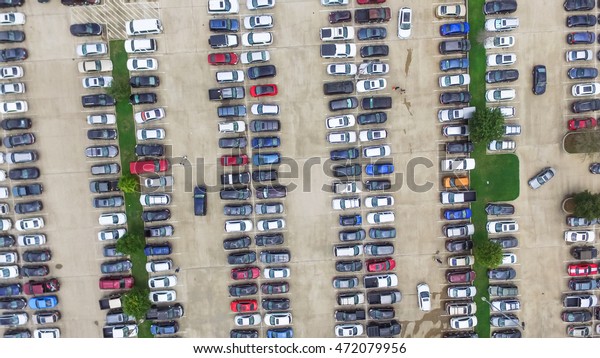 Aerial view full cars at large outdoor parking\
lots in Houston, Texas, USA. Outlet mall parking congestion and\
crowded parking lot, other cars try getting in and out, finding\
parking space. Panorama