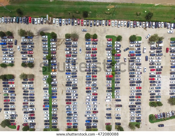 Aerial view full cars at large outdoor parking\
lots in Houston, Texas, USA. Outlet mall parking congestion and\
crowded parking lot with other cars try getting in and out, finding\
parking space.