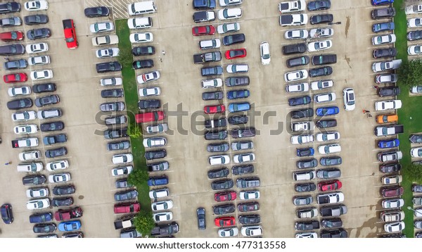 Aerial view full cars at large outdoor parking\
lots in Houston, Texas, USA. Outlet mall parking congestion and\
crowded parking lot, other cars try getting in and out, finding\
parking space. Panorama