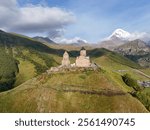 Aerial view of Gergeti Trinity Church in Caucasus Mountains near Stepantsminda village in Georgia. Mount Kazbek and majestic snow-covered peaks around.