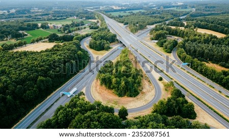 Aerial view of German highway autobahn . Drone shot of highway  among forest and green field. Cars fast speed moving on freeway.