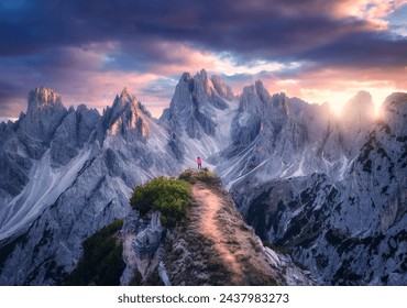 Aerial view of girl on the mountain peak and rocks at colorful sunset in summer. Tre Cime, Dolomites, Italy. Top drone view of woman on trail, cliffs, grass, sky, clouds, sunlight in spring. Hiking	 - Powered by Shutterstock