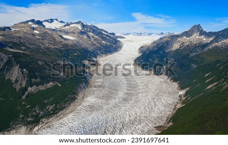 Aerial view of the glaciers located along the Taku Inlet, which are part of the Juneau Icefield in Alaska, USA - Curvy flow of ice covered with shear crevasses, cracks and fissures