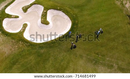 Aerial view of golfers playing on putting green. Professional players on a green golf course.