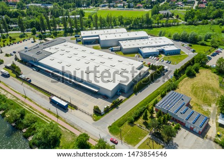 Aerial view of goods warehouse. Logistics center in industrial city zone from above. Aerial view of trucks loading at logistic center. View from drone. 