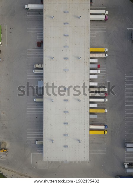 Aerial view of goods warehouse. Logistics\
center in industrial city zone from above. Aerial view of trucks\
loading at logistic center. View from\
drone.
