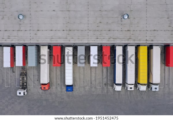 Aerial view of goods warehouse. Logistics
center in industrial city zone from above. Aerial view of trucks
loading at logistic center. View from
drone.	
