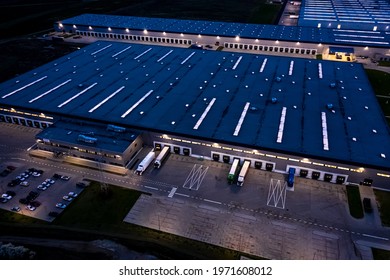 Aerial view of goods warehouse at Night. Logistics center in industrial city zone from above. Aerial view of trucks loading at logistic center. View from drone. - Powered by Shutterstock