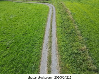 Aerial view of gravel road between meadow