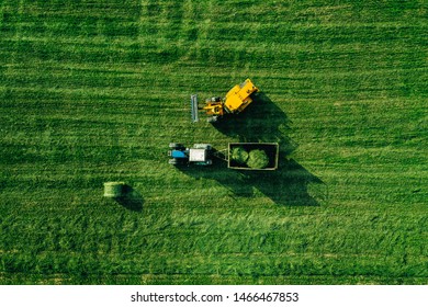 Aerial View Of Green Grass Harvest Field With Tractor Moving Hay Bale