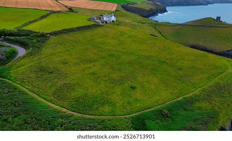 Aerial view of a green landscape with a solitary white house near the coast. In Cornwall, UK. - Powered by Shutterstock