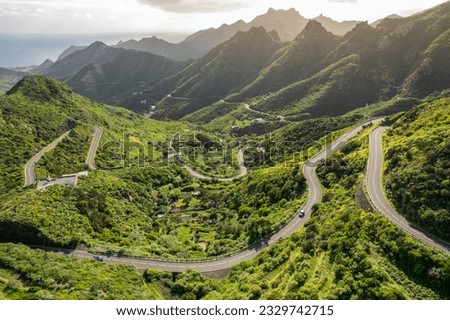 Aerial view of green volcanic landscape with serpentine road in northern part of Tenerife, Canary islands, Spain. Mountain road in Tenerife at sunset.