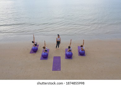 Aerial view of group of Asian women in yoga class club doing exercise and yoga at natural beach and sea coast outdoor in sport and recreation concept. People lifestyle activity. - Powered by Shutterstock