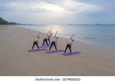 Aerial view of group of Asian women in yoga class club doing exercise and yoga at natural beach and sea coast outdoor in sport and recreation concept. People lifestyle activity. - Powered by Shutterstock