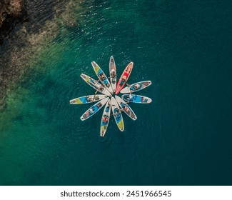 aerial view of a group of paddleboarders forming a star pattern on the clear blue waters - Powered by Shutterstock