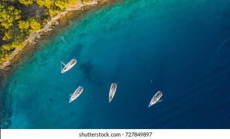 Aerial view of group of sailing boats anchoring next to reef. Bird eye view, water sport theme. - Powered by Shutterstock