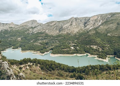 Aerial view of the Guadalest reservoir between mountains on a cloudy day