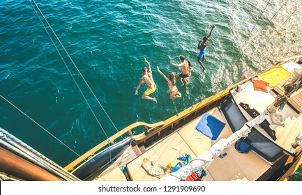 Aerial View Of Happy Millenial Friends Jumping From Sailboat On Sea Ocean Trip - Rich Guys And Girls Having Fun Together In Exclusive Boat Party Day - Luxury Vacation Concept On Contrast Bright Filter