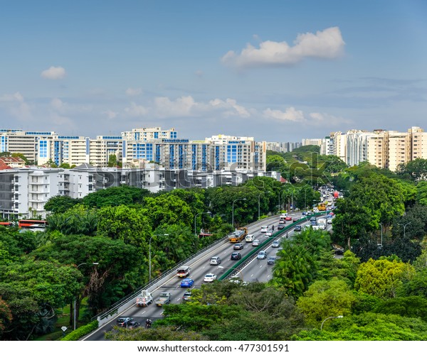 Aerial view HDB housing complex near highway\
with lot of green trees and vehicles in traffic, cloud blue sky.\
Singapore is an excellent green, clean city. Asia transportation,\
infrastructure concept.