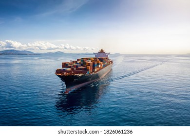 Aerial view of a heavy loaded container cargo vessel traveling over calm, blue sea
