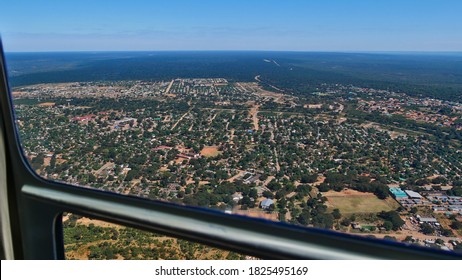 Aerial View From Helicopter Over Famous Victoria Falls Town And Bush Land At The Border Of Zimbabwe And Zambia On A Sunny Day With Blue Sky.