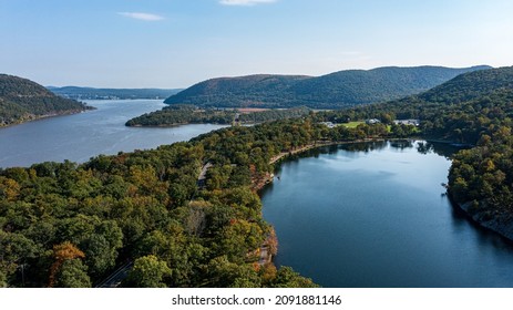Aerial view, high up over a calm Hudson River on a sunny day with blue skies, it is a high angle shot, taken with a drone camera by the Bear Mountain Bridge.