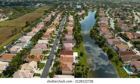 An Aerial View High Over A Reflective Pond, Surrounded By Beautiful Houses In A Residential Neighborhood On A Sunny Day In Margate, Florida.