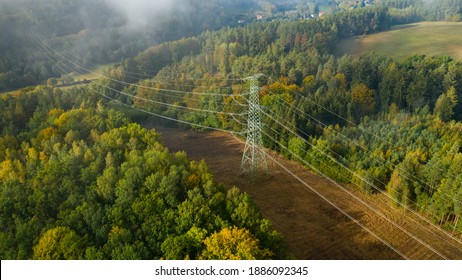 Aerial view of the high voltage power lines and high voltage electric transmission on the terrain surrounded by trees at sunlight