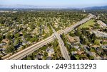 Aerial view of Highway 85 cutting through a residential neighborhood in Saratoga, California, framed by distant mountains surrounding Silicon Valley