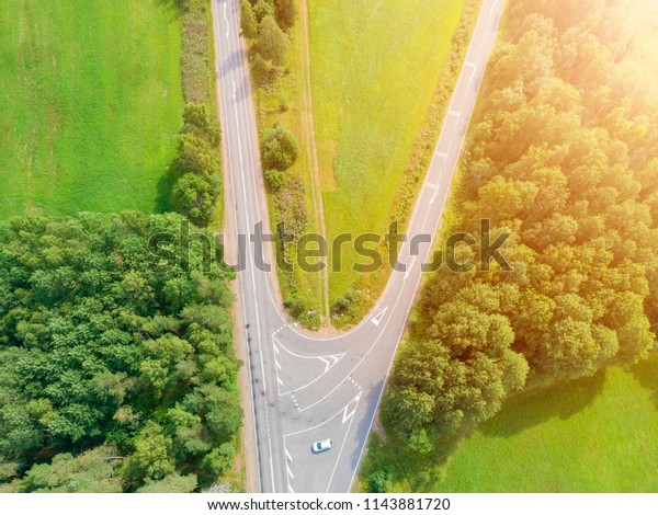 Aerial view of highway\
with car. Aerial view of a country road with moving car. Car\
passing by. Aerial road. Aerial view flying. Captured from above\
with a drone. Soft\
lighting