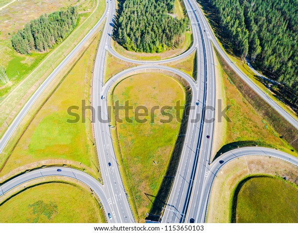 Aerial view of highway in city. Cars crossing\
interchange overpass. Highway interchange with traffic. Aerial\
bird\'s eye photo of highway. Expressway. Road junctions. Car\
passing. Top view from above.\
