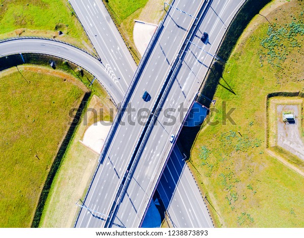 Aerial view of highway in city. Cars crossing\
interchange overpass. Highway interchange with traffic. Aerial\
bird\'s eye photo of highway. Expressway. Road junctions. Car\
passing. Top view from above.\
