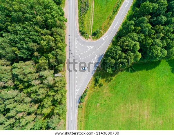Aerial view of highway. Aerial view of a\
country road with moving car. Car passing by. Aerial road. Aerial\
view flying. Captured from above with a\
drone.