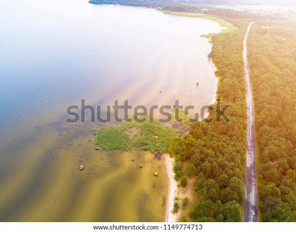 Aerial view of highway.\
Aerial view of a country road near the lake. Car passing by. Aerial\
road. Aerial view flying. Captured from above with a drone. Soft\
lighting