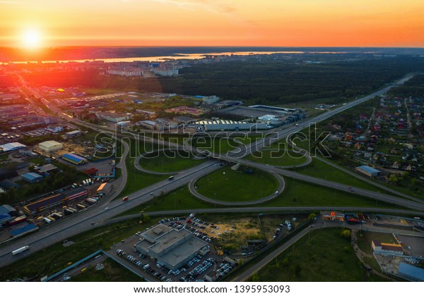 Aerial view at highway intersection or road\
junction with circle movement at sunset, cars and trucks traffic,\
drone shot, toned