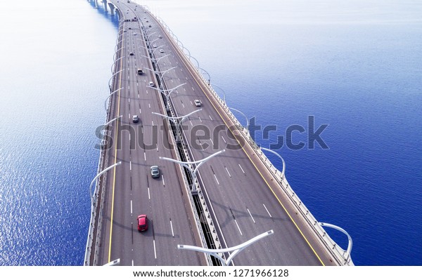 Aerial view of highway in the ocean. Cars\
crossing bridge interchange overpass. Highway interchange with\
traffic. Aerial bird\'s eye highway. Expressway. Road junction. Car\
passing. Bridge with\
traffic