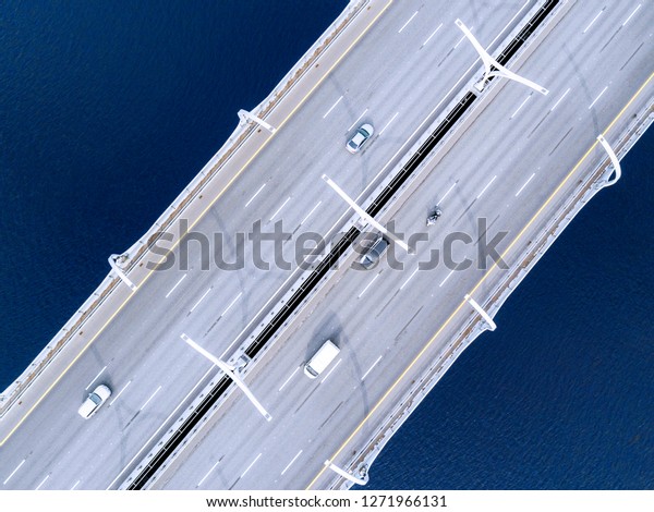 Aerial view of highway in the ocean. Cars\
crossing bridge interchange overpass. Highway interchange with\
traffic. Aerial bird\'s eye highway. Expressway. Road junction. Car\
passing. Bridge with\
traffic
