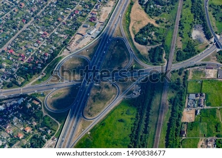 Aerial view of a highway and overpass with green forests and houses on a summer day.