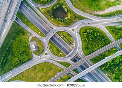 Aerial View Of Highway Road Junction. Highways, Railway And Green Fields On The Outskirts Of The City. Transport Concept.