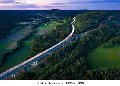 Aerial view of highway splitting aound forest hill on autumn evening, long exposure - Powered by Shutterstock