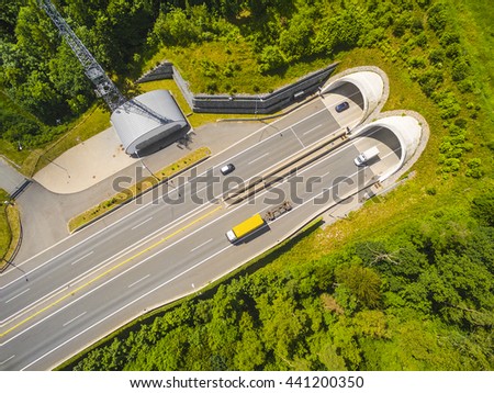 Aerial view of highway tunnel in mountains. Traffic on the road. Transportation from above. Industrial background.