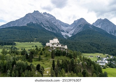 Aerial view of a historic castle nestled in green valleys surrounded by majestic mountains in the Alps during daylight - Powered by Shutterstock