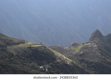 Aerial view of historic old peruvian secret Inca ruin, ancient UNESCO tourist landmark Machu Picchu with traditional stone wall houses and scenic mountain landscape near Cusco, Peru, South America.
