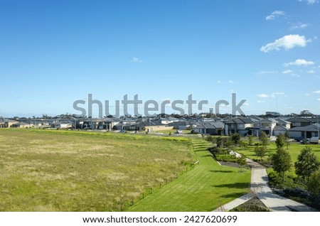 Aerial view of houses in the neighbourhood, and a large block of vacant land. A new suburb with many modern family homes in Point Cook, Melbourne VIC Australia. Copy space for your design.