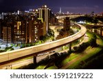 Aerial view of HuanDong Boulevard, an elevated expressway along Keelung River in Nangang, Taipei City, & 101 Tower standing out amid the dazzling lights of crowded buildings in Xinyi District at night