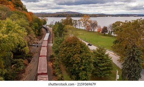 An Aerial View Of The Hudson River Surrounded By Autumnal Foliage With A Train Passing By