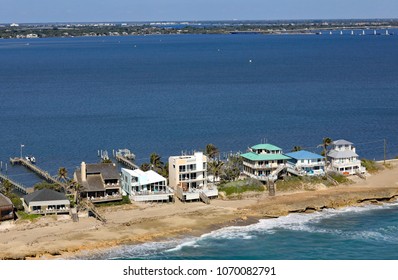Aerial view of Hutchinson Island, Florida with a cluster of homes on the barrier island, fronting on to the Atlantic Ocean, and with docks on the protected side of the island and lagoon.