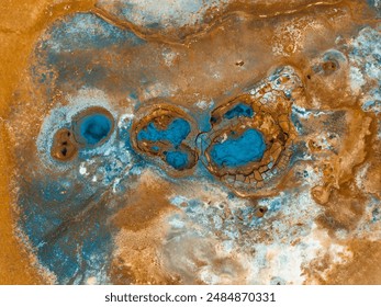 Aerial view of Hverir Geothermal Area, Iceland, showcasing vibrant blue and orange geothermal pools and mud pits in a surreal landscape. - Powered by Shutterstock