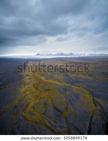 Aerial view of Icelandic black sand landscape with mountains and clacier in the background in Haoldukvisl, Iceland