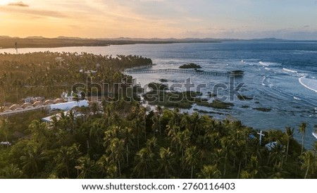 Aerial view of the iconic Cloud 9 wooden boardwalk in General Luna, Siargao, Philippines. The golden evening light reflects on the waves of the famous surfing destination
